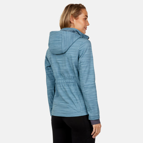 A woman with blonde hair wears the Free Country Women's Aeris II Super Softshell® Jacket in light blue and black pants, standing with her back and side to the camera against a plain light gray background.