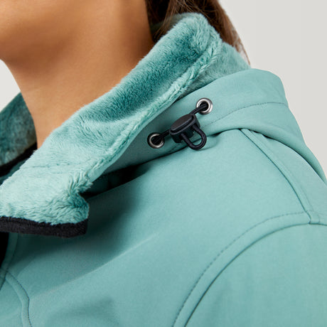 Close-up of a person wearing the Clearance Women's FreeCycle® Super Softshell® Jacket, featuring a teal color, soft fuzzy lining, and drawstring toggle at the collar. The image highlights the texture on the shoulder and neck area.