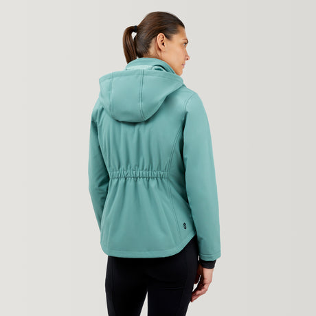 A woman with brown hair in a ponytail wears the Clearance Women's FreeCycle® Super Softshell® Jacket in light teal and black pants, standing with her back to the camera against a plain, light gray background.