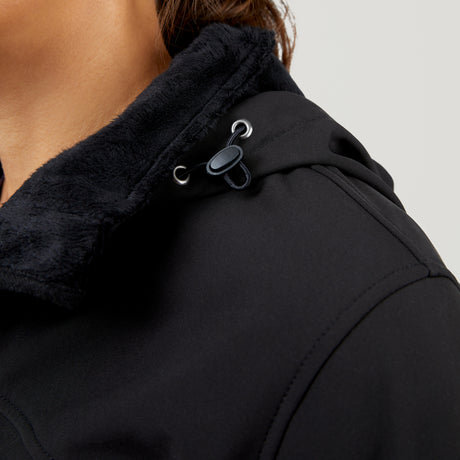 Close-up of a person wearing the Clearance Women's FreeCycle® Super Softshell® Jacket in black, featuring a water-resistant finish, soft fuzzy collar, and adjustable drawstring with plastic toggle, shown from the neck and shoulders.