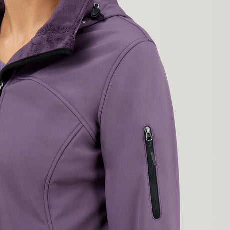 Close-up of a person in the Clearance Women's FreeCycle® Super Softshell® Jacket, featuring four-way stretch fabric, zippered sleeve pocket, black fleece-lined collar, and a hood with a visible drawstring toggle.