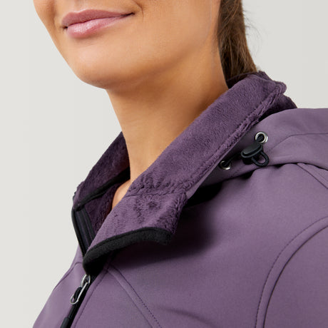 Close-up of a woman smiling in the Women's FreeCycle® Super Softshell® Jacket by Clearance, featuring a plush inner collar, black zipper, and four-way stretch fabric. The focus is on the collar detail, part of her face, and shoulder.