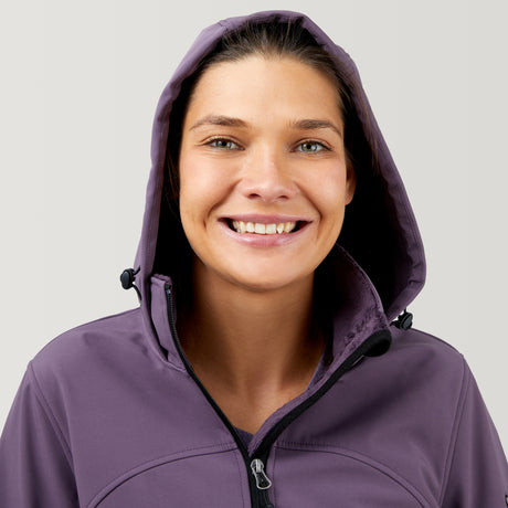 A light-skinned woman with brown hair smiles, wearing the Clearance Women's FreeCycle® Super Softshell® Jacket in purple with the hood up, against a plain light background.