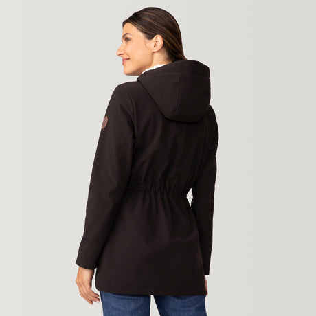 [Olga is 5’9" wearing size S.] Woman wearing Free Country Women's FreeCycle® Long Super Softshell® Jacket in black with a full front zipper opening, soft lining, cinched back waist, an attached hood with an adjustable drawcord, and water resistant and wind resistant performance fabric, light grey background. Best women’s jacket for chilly weather.
