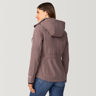 [Olga is 5’9” wearing a size Small.] Woman wearing Free Country Women's Aeris II Super Softshell® Jacket in light brown with a full front zipper opening, soft lining, detachable hood, and water resistant and wind resistant stretch performance fabric, light grey background. Perfect women’s  jacket for fall weather.