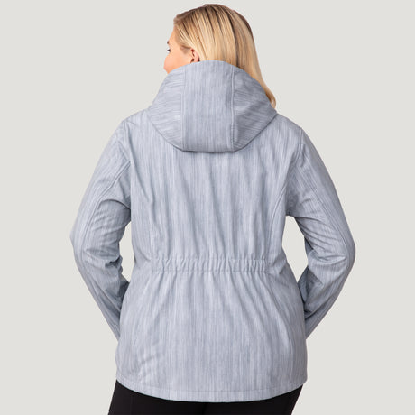 A woman with blonde hair is shown from the back wearing the Free Country Women's Plus Size Aeris II Super Softshell® Jacket in light gray, featuring water-resistant, three-layer bonded fabric, subtle vertical stripes, and an elastic waistband.