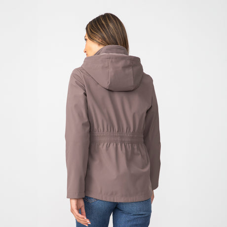 [Olga is 5’9" wearing a size Small.] Woman wearing Free Country Women's TrailTrek Super Softshell® Jacket in brown with a full front zipper opening, lower pockets, soft lining, a hood with an adjustable drawcord, and water resistant and wind resistant stretch performance fabric, light grey background. Best women’s jacket for winter weather.