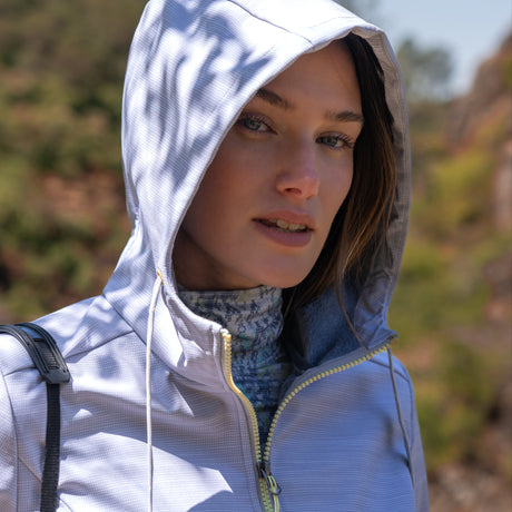 Woman wearing Free Country Women's Alps Super Softshell® Jacket in textured ligth grey with a full front zipper opening, soft lining, attached hood with adjustable drawcords, and water resistant and wind resistant stretch performance fabric. Perfect women’s  jacket for fall weather.