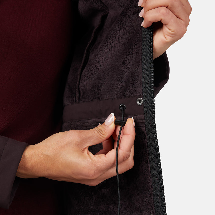 [Jessica is 5'9.5" wearing size S.] Women’s dark-brown hooded softshell jacket with zip-front closure, flap chest pockets, and adjustable drawstrings—features a sleeve patch and is paired with dark pants for a rugged, outdoor-ready look.