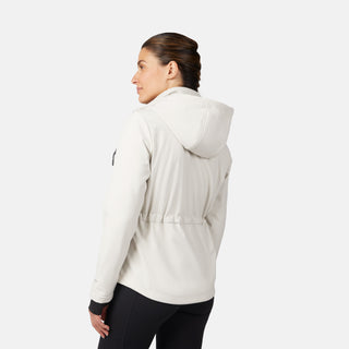 A woman with dark braided hair wears the Free Country Women's StormTech Super Softshell® Jacket and black leggings, standing against a white background, facing away and looking over her left shoulder.