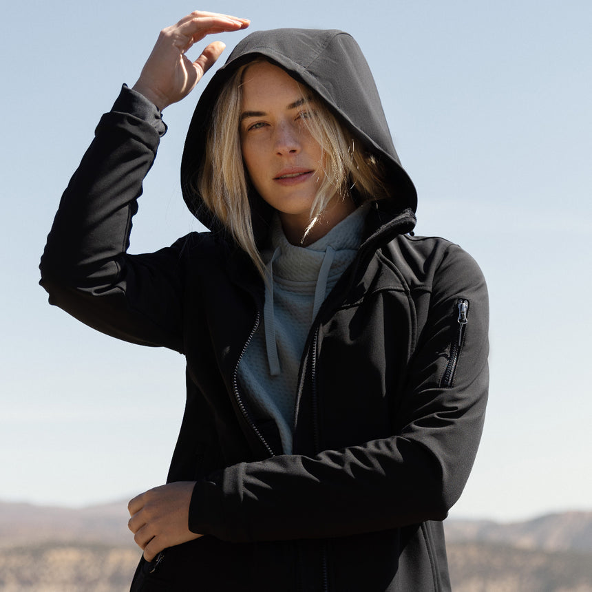 Person wearing a black jacket with a hood outdoors