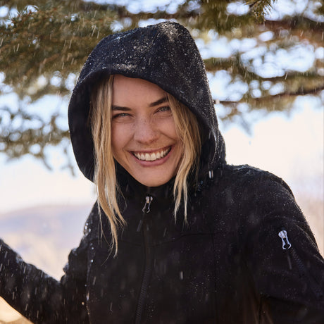 Person wearing a black hooded jacket in a snowy outdoor setting