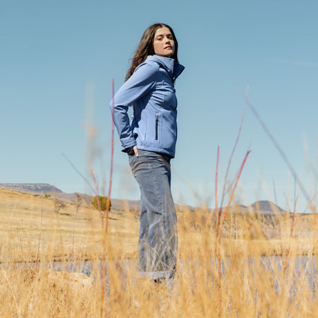 Person wearing a blue jacket standing in a field with a clear sky