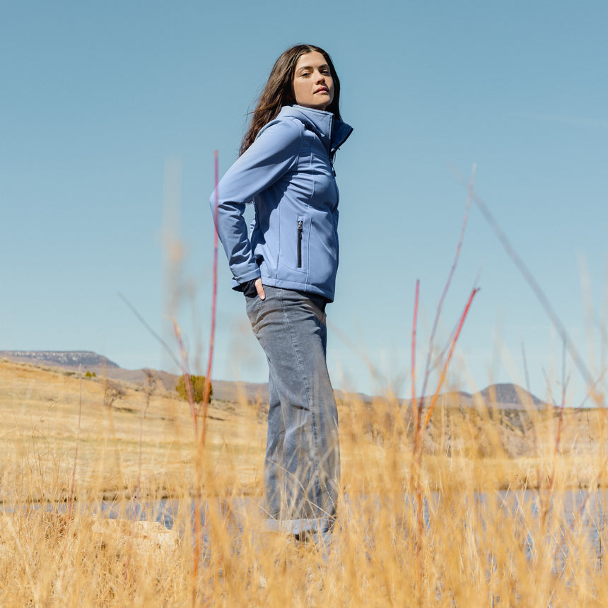 Person wearing a blue jacket standing in a field with a clear sky