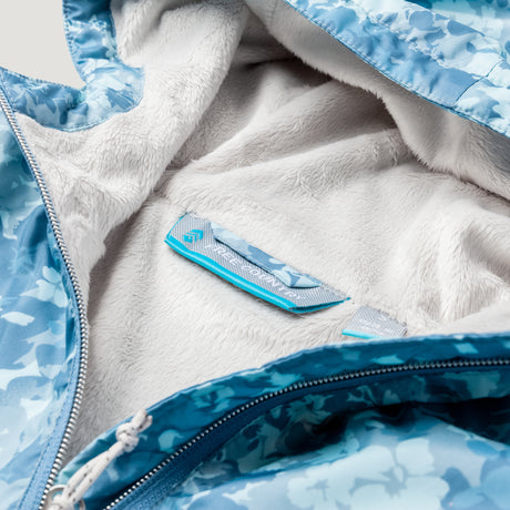 Close-up of the Clearance Women's Windshear Jacket: blue floral-patterned, water-resistant fabric with a soft white fleece lining, zipper details, and a blue-gray interior label.