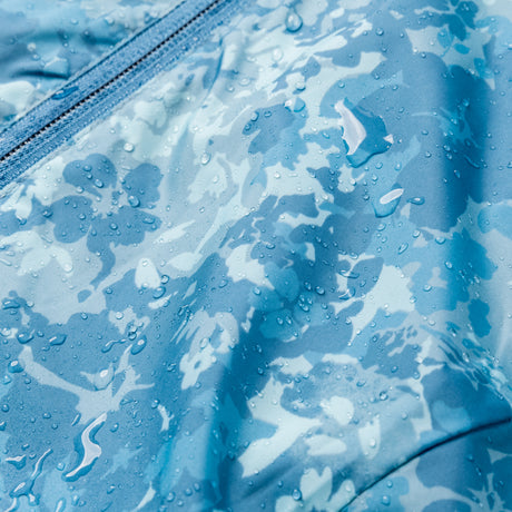 Close-up of blue floral camouflage fabric with water droplets, showcasing the Women's Windshear Jacket by Clearance and its stylish water resistant quality—ideal for a fashionable windbreaker.