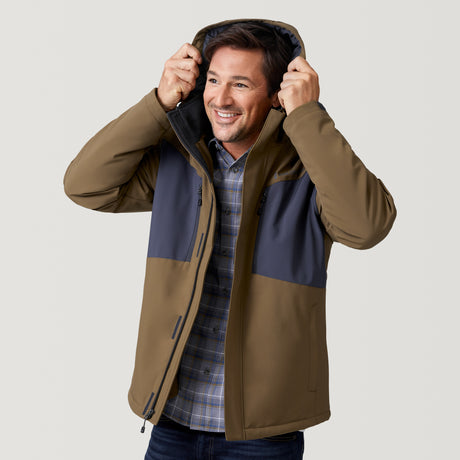 A smiling man wears the Clearance Men's Thermo Softshell® Mid Weight Jacket in brown and gray over a plaid shirt, holding up the hood with both hands against a plain light background.
