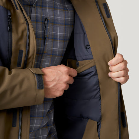 A person wears the Men's Thermo Softshell® Mid Weight Jacket by Clearance over a plaid shirt, opening it to reveal a secure inner pocket and showcase the jacket's interior details and features.