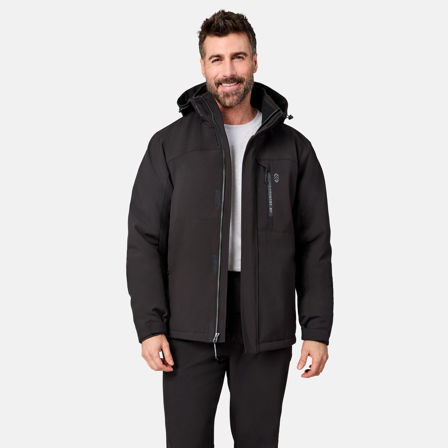 [Model is wearing size M.] A man wearing a black hooded jacket with a front zipper, zippered chest pocket, and a vertical logo on the pocket, paired with a white t-shirt and black pants, against a light gray background.