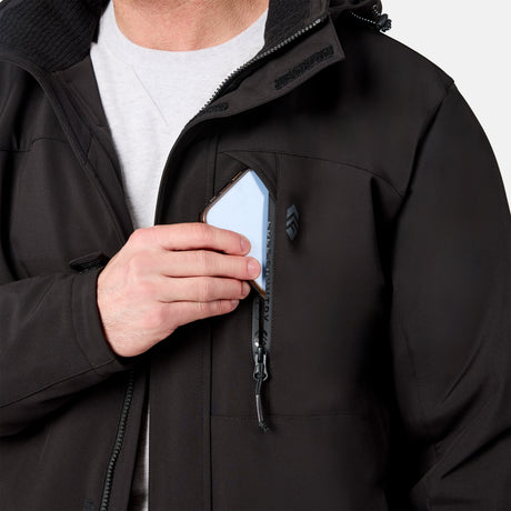 [Model is wearing size M.] Close-up of a person wearing a black softshell jacket over a light gray shirt, demonstrating a zippered chest pocket that fits a smartphone.