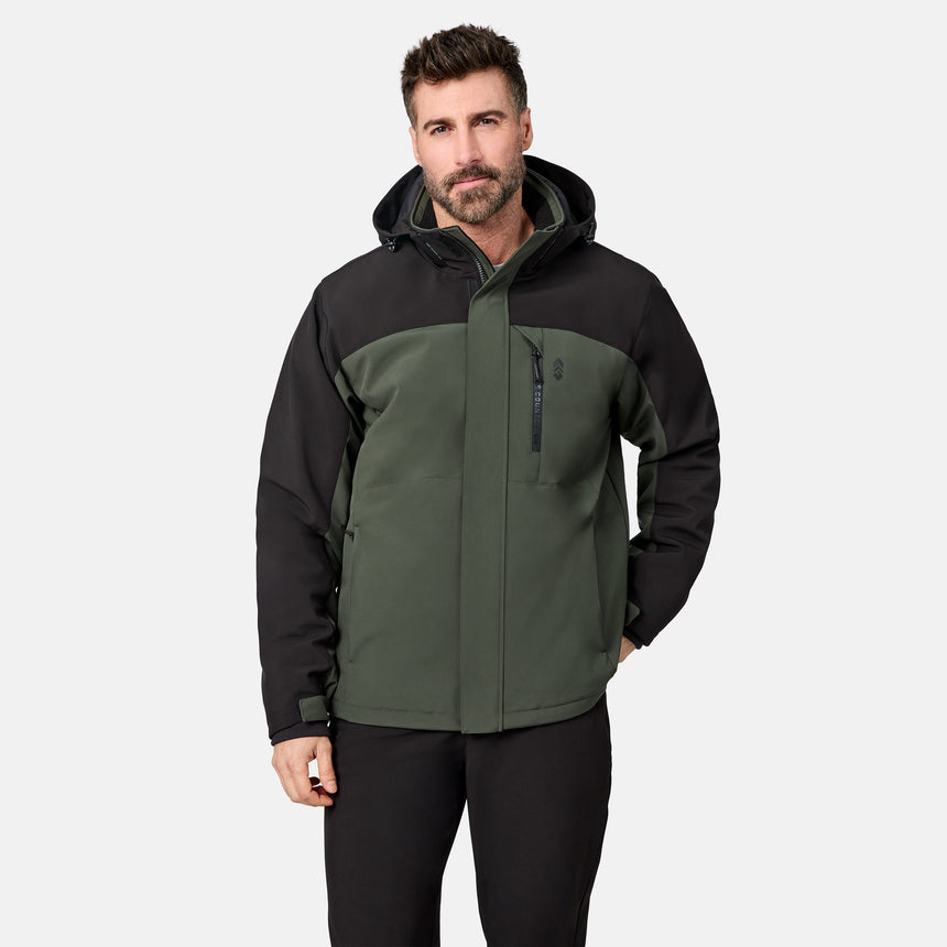 [Model is wearing size M.] A man wearing a hooded outdoor jacket in dark green and black, paired with black pants, photographed against a light gray studio background.