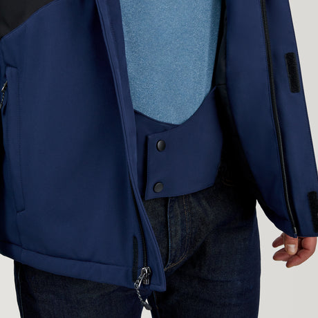 A person wears the Clearance Men's Thermo Softshell® Mid Weight Jacket in blue, unzipped to reveal its snap button inner lining and side black zipper, layered over a lighter blue shirt and paired with dark jeans.