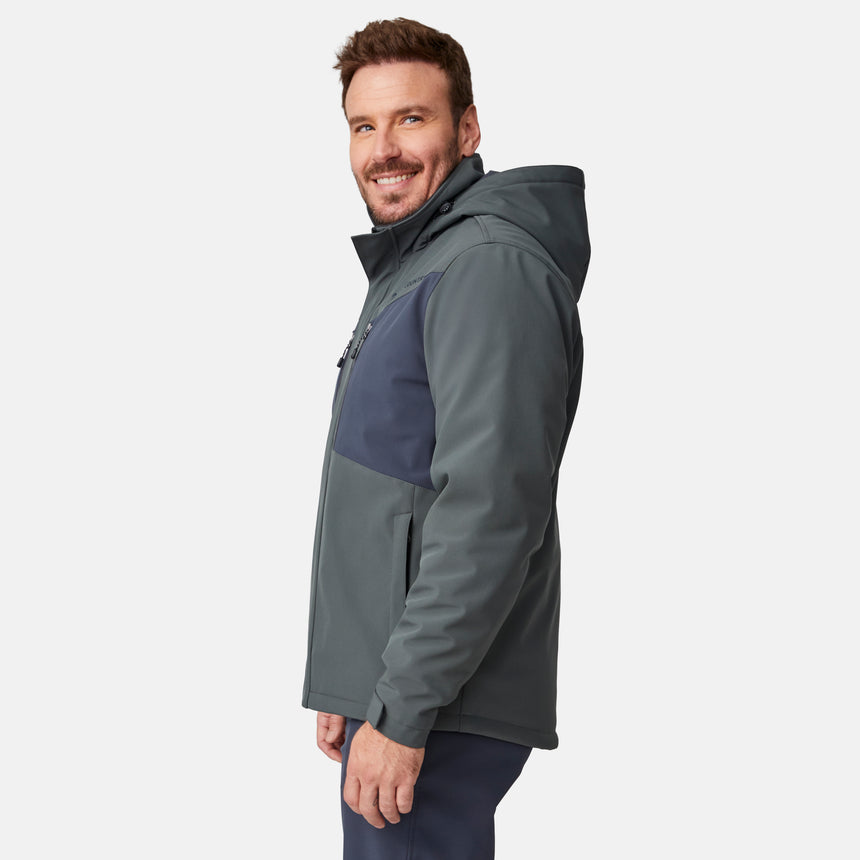 [Joe is 6'0" wearing size M.] Men’s Free Country two-tone hooded zip-front jacket with dark gray body and black paneling across shoulders and chest—features dual vertical zippered chest pockets, side hand pockets, full-length front zipper, and an attached interior snow skirt for enhanced protection against the elements. Paired with matching gray pants for a sleek, coordinated winter look.