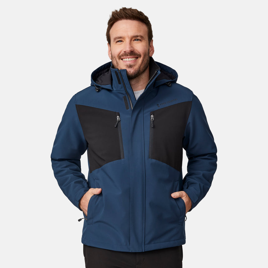 [Joe is 6'0" wearing size M.]  "Men’s Free Country hooded zip-front jacket with black chest panels and deep blue sleeves and body—features dual vertical zippered chest pockets, side hand pockets, full-length zipper closure, and an attached interior snow skirt for added protection against snow and wind. Styled with black pants for a sleek, functional cold-weather look.