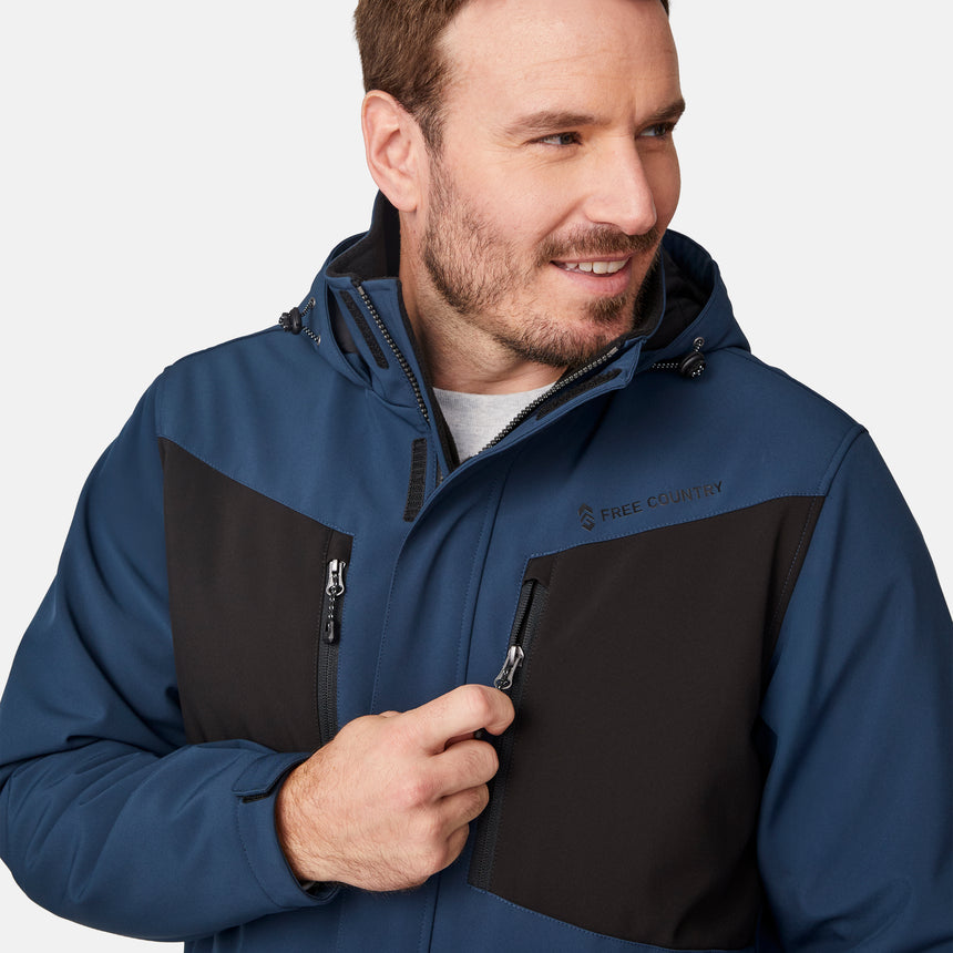 [Joe is 6'0" wearing size M.]  "Men’s Free Country hooded zip-front jacket with black chest panels and deep blue sleeves and body—features dual vertical zippered chest pockets, side hand pockets, full-length zipper closure, and an attached interior snow skirt for added protection against snow and wind. Styled with black pants for a sleek, functional cold-weather look.