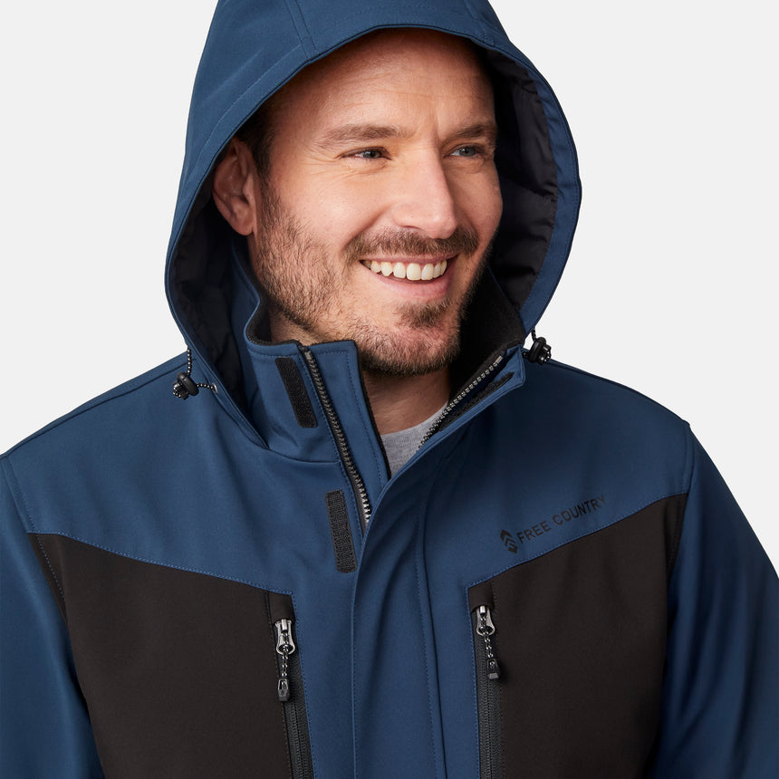 [Joe is 6'0" wearing size M.]  "Men’s Free Country hooded zip-front jacket with black chest panels and deep blue sleeves and body—features dual vertical zippered chest pockets, side hand pockets, full-length zipper closure, and an attached interior snow skirt for added protection against snow and wind. Styled with black pants for a sleek, functional cold-weather look.