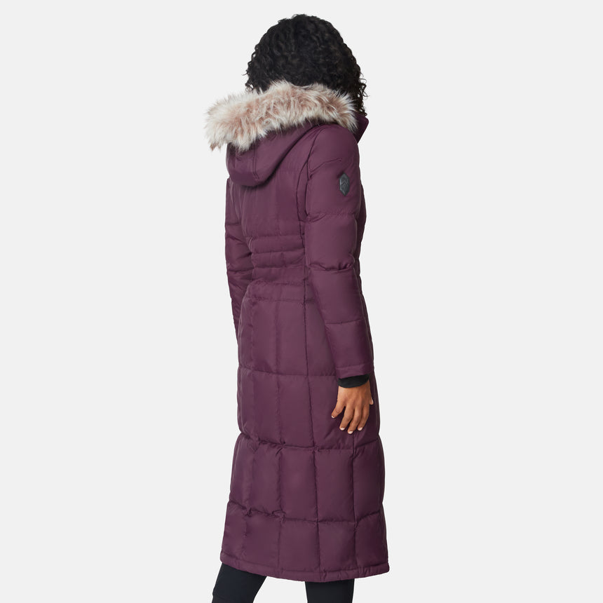 [Angelique is 5'10" wearing size S.] Woman wearing Free Country Women's Full Length Splendor Down Jacket in burgundy with a full front zipper opening, lower pockets, calf length, a detachable hood with faux fur trim, and water resistant and wind resistant stretch performance fabric, light grey background. Best women’s jacket for winter weather.