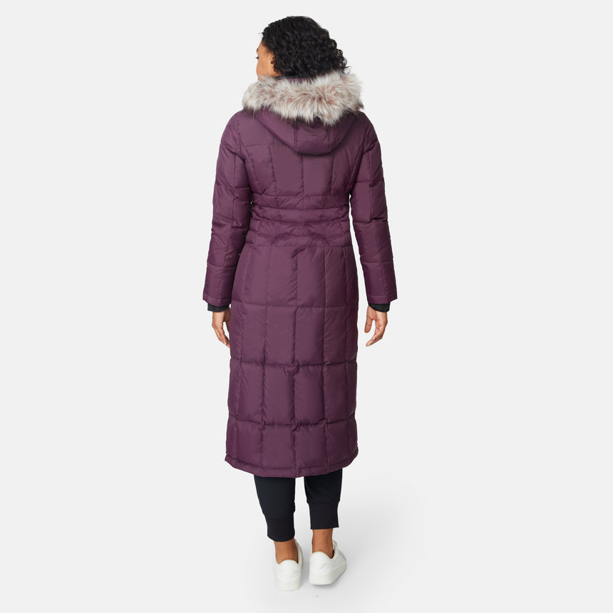 [Angelique is 5'10" wearing size S.] Woman wearing Free Country Women's Full Length Splendor Down Jacket in burgundy with a full front zipper opening, lower pockets, calf length, a detachable hood with faux fur trim, and water resistant and wind resistant stretch performance fabric, light grey background. Best women’s jacket for winter weather.