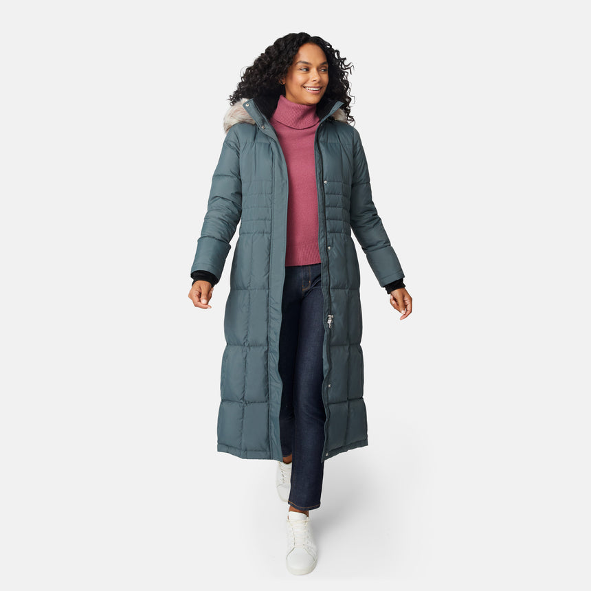 [Angelique is 5'10" wearing size S.] Woman wearing Free Country Women's Full Length Splendor Down Jacket in green with a full front zipper opening, lower pockets, calf length, a detachable hood with faux fur trim, and water resistant and wind resistant stretch performance fabric, light grey background. Best women’s jacket for winter weather.