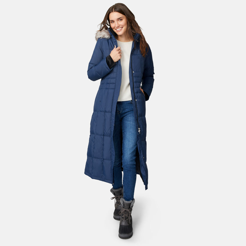 [Jessica is 5'9.5" wearing size S.] Woman wearing Free Country Women's Full Length Splendor Down Jacket in navy blue with a full front zipper opening, lower pockets, calf length, a detachable hood with faux fur trim, and water resistant and wind resistant stretch performance fabric, light grey background. Best women’s jacket for winter weather.