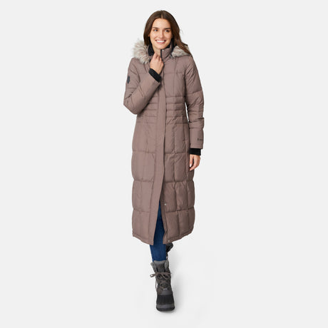 [Jessica is 5'9.5" wearing size S.] Woman wearing Free Country Women's Full Length Splendor Down Jacket in tan with a full front zipper opening, lower pockets, calf length, a detachable hood with faux fur trim, and water resistant and wind resistant stretch performance fabric, light grey background. Best women’s jacket for winter weather.