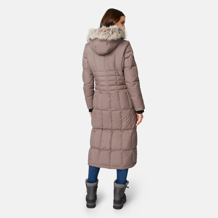 [Jessica is 5'9.5" wearing size S.] Woman wearing Free Country Women's Full Length Splendor Down Jacket in tan with a full front zipper opening, lower pockets, calf length, a detachable hood with faux fur trim, and water resistant and wind resistant stretch performance fabric, light grey background. Best women’s jacket for winter weather.