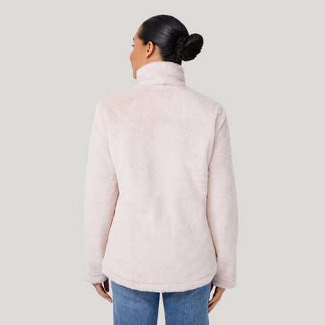 A woman with dark hair in a neat bun is shown from behind, modeling the Clearance Women's FreeCycle® Cloud Lite II Reversible Jacket in light pink with blue jeans against a plain light gray background.