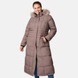 A woman smiles with one hand in her pocket, wearing the Free Country Women's Plus Size Full Length Splendor Down Jacket in taupe with a faux fur–trimmed hood and water-resistant finish, set against a plain white background.