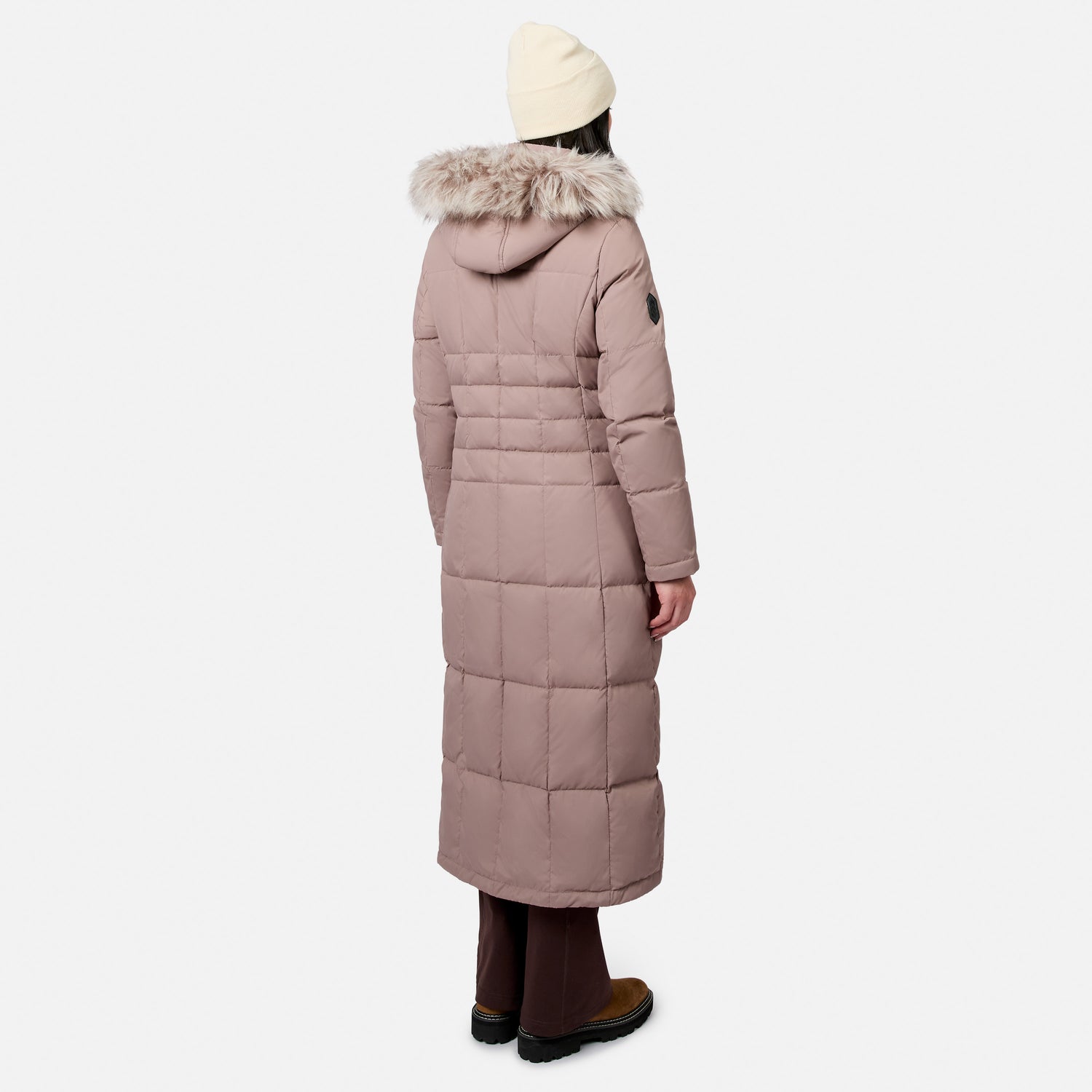 Back view of a model wearing a dusty pink full length Splendor Down Jacket with a fur lined hood.