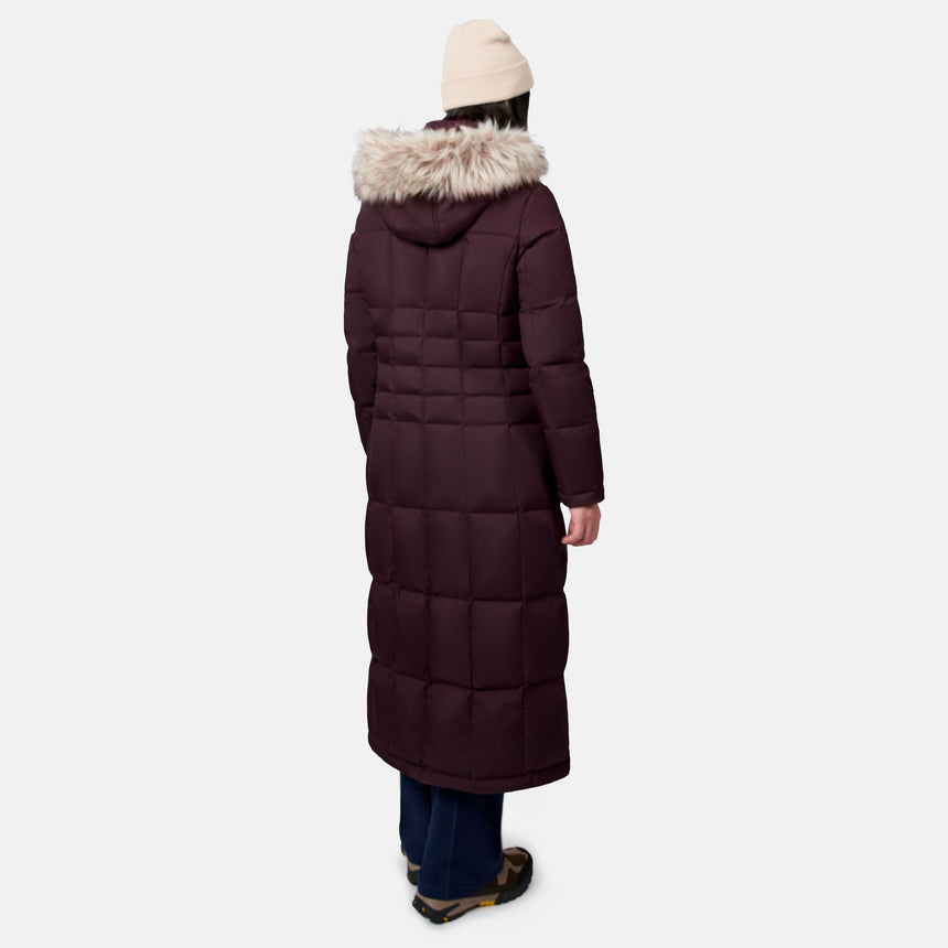 Back view of burgundy Splendor Down Jacket with fur hood in a snowy outdoor setting wearing a cream knit beanie