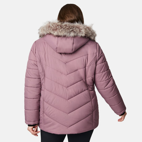 A woman is shown from the back in a mauve Free Country Women's Plus Size Unstoppable II Poly Air Touch Jacket with a fur-trimmed hood, set against a plain white background.