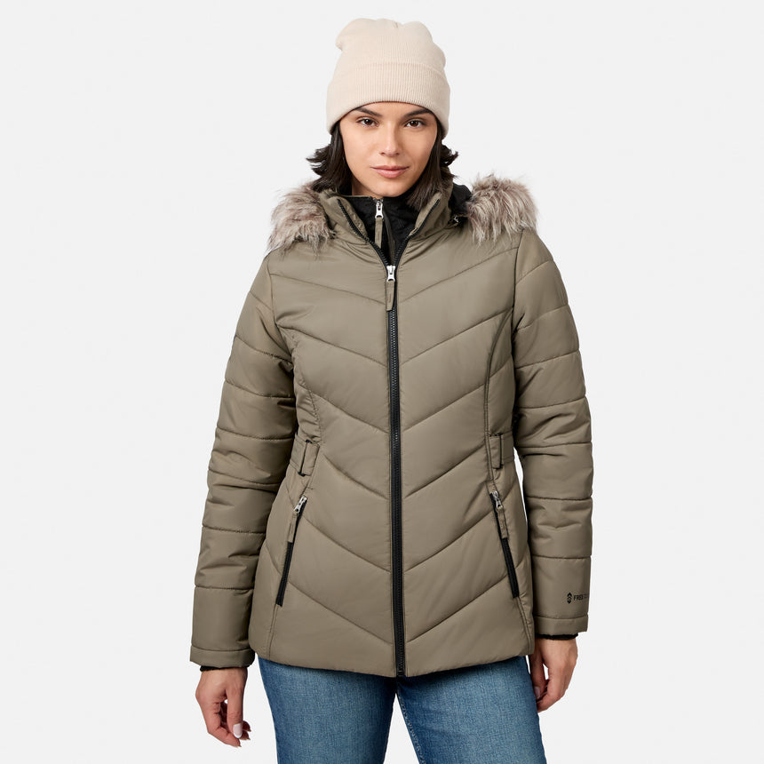 [Model is wearing size S.] A woman wearing a light brown puffer jacket with a faux-fur trimmed hood, a beige knit beanie, and blue jeans, photographed against a light gray studio background.