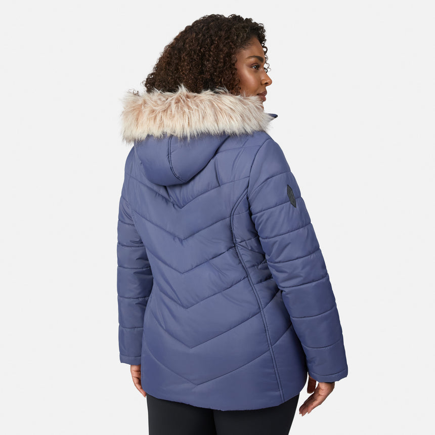 [Model is wearing size 1X] A woman wearing a blue quilted puffer jacket with a fluffy beige faux-fur trimmed hood, shown from a back-three-quarter view against a light gray studio background.