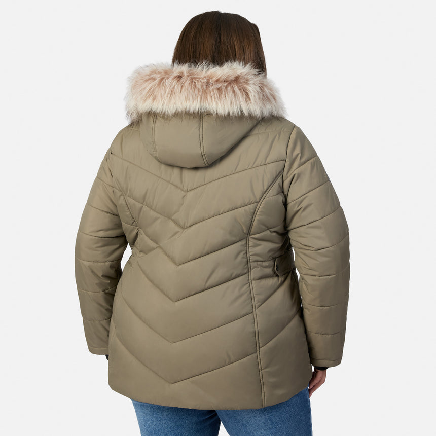 [Model is wearing size 1X] A woman viewed from the back wearing a quilted puffer jacket in taupe with a light beige faux-fur trimmed hood, paired with blue jeans, against a light gray studio background.