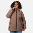 [Model is wearing size 1X] A woman wearing a taupe-brown quilted puffer jacket with a light beige faux-fur trimmed hood and black zippers, paired with blue jeans, against a light gray studio background.