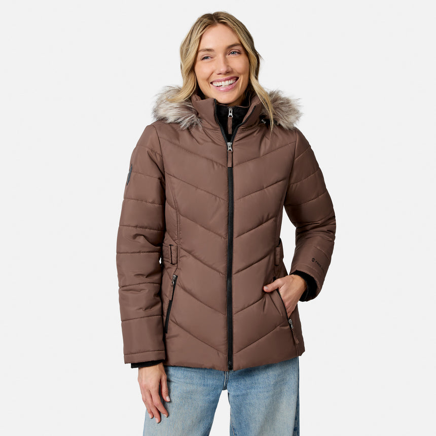 [Model is wearing size S.] A woman wearing a brown puffer jacket with a faux-fur trimmed hood and a black front zipper, paired with light blue jeans, against a light gray studio background.