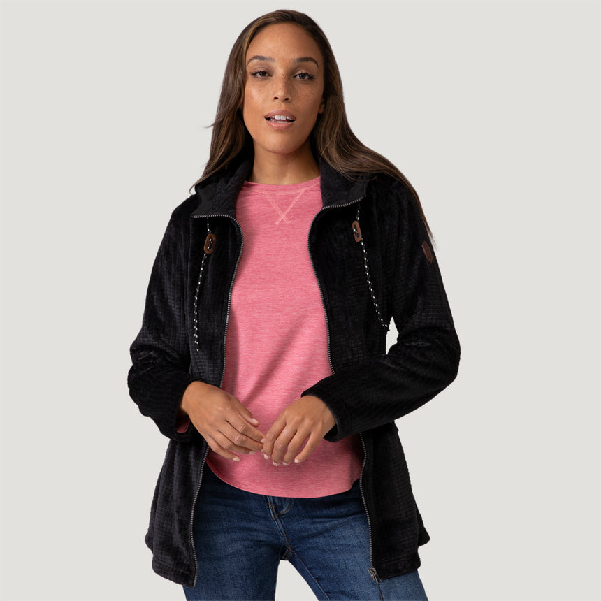 [Model is wearing size S.] Women’s Free Country black textured zip-front hooded jacket with wooden toggle drawstrings and dual side pockets—layered over a pink shirt and paired with blue jeans for a casual, cool-weather look.