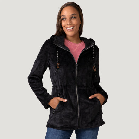 [Model is wearing size S.] Women’s Free Country black textured zip-front hooded jacket with wooden toggle drawstrings and dual side pockets—layered over a pink shirt and paired with blue jeans for a casual, cool-weather look.