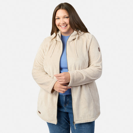 A woman with long brown hair smiles, wearing the Free Country Women’s Plus Size Grid Butter Pile® Anorak Jacket over a blue shirt and jeans, standing against a plain white background.