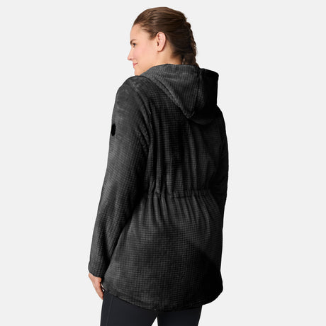 A woman with brown hair in a braid wears the Free Country Women’s Plus Size Grid Butter Pile® Anorak Jacket in black, standing with her back to the camera and looking left against a plain light gray background.